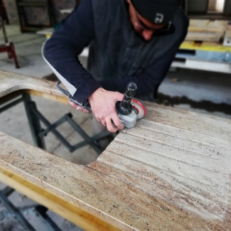 Finitura manuale del gocciolatoio di un piano cucina in granito Ivory Fantasy.