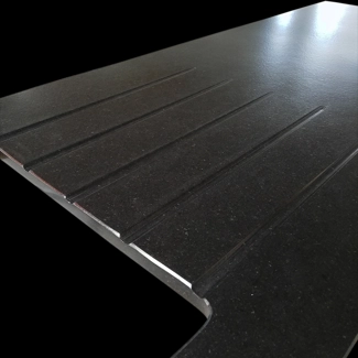 Dettaglio di gocciolatoio solo gusce levigate su piano cucina in granito Nero Assoluto spazzolato.