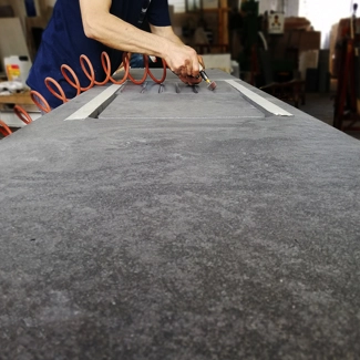 Finitura manuale delle gusce su piano cucina in granito.